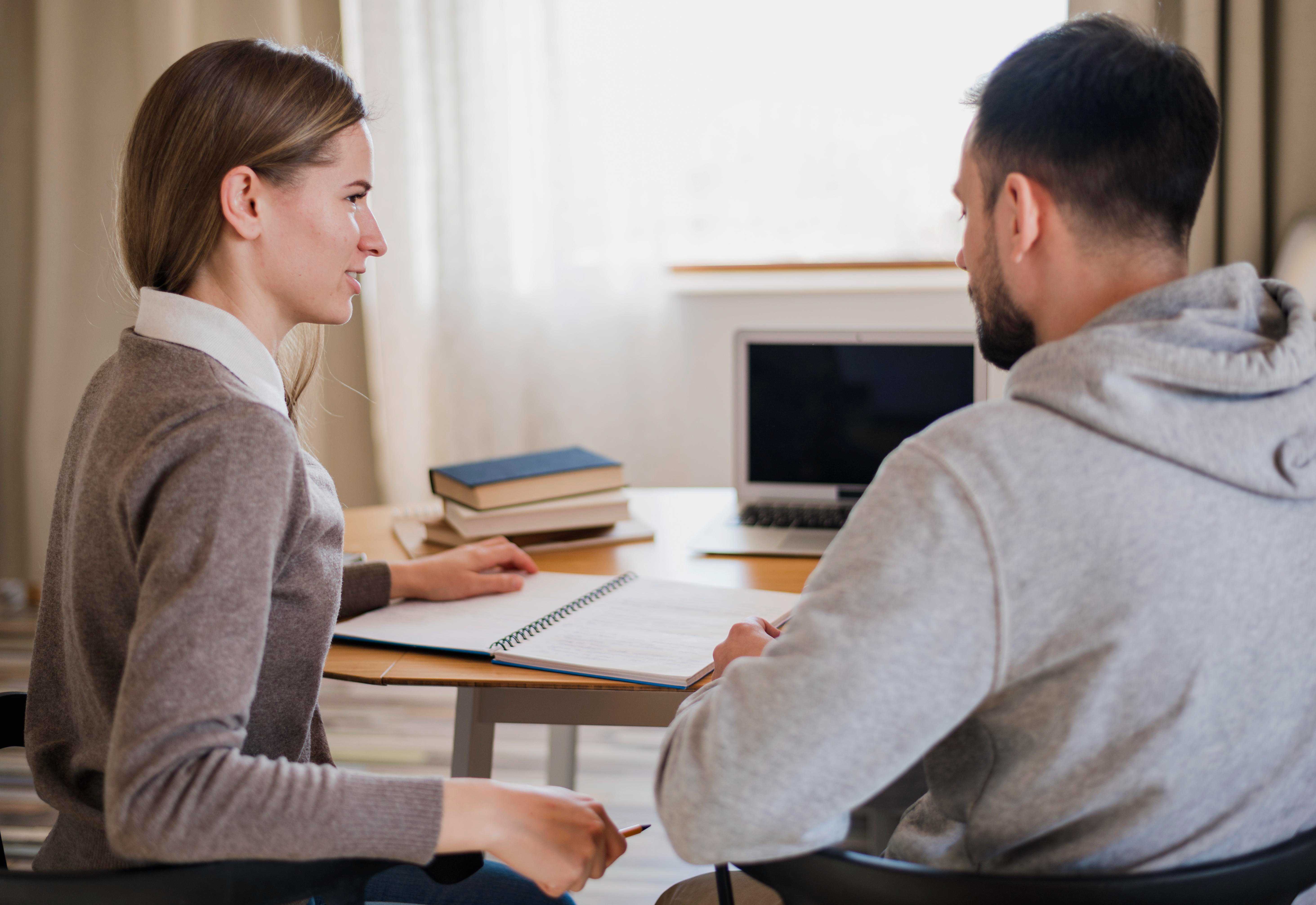 woman and man sat at desk working on notebook